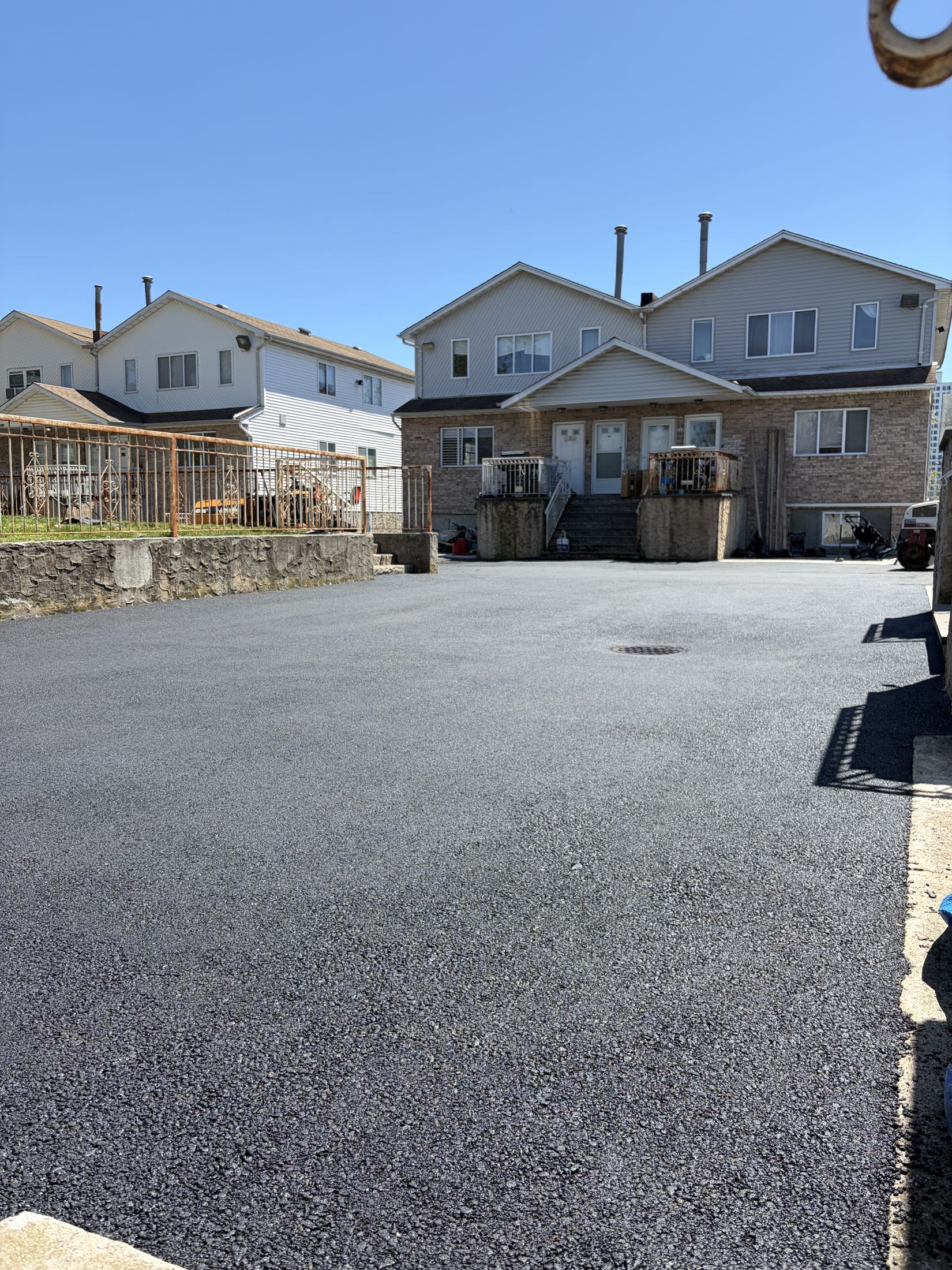 Freshly paved asphalt parking area behind homes in Far Rockaway, New York